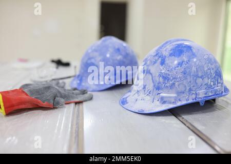 Two dirty hard hats and gloves on plastic panels close up. Stock Photo