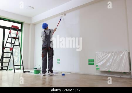 Professional painter paints office wall with roller brush. Stock Photo
