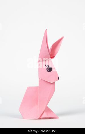 A pink origami rabbit on a white background. Crafts for Easter, fold from paper, do it yourself Stock Photo