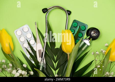 Bouquet of flowers and stethoscope on a green background, happy doctors day, nurses week and other medical holidays. Stock Photo