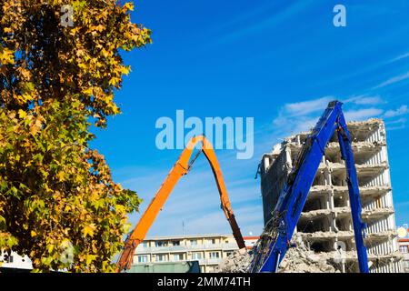 Demolition of the old building with sloopkraan against blue clouds sky. Stock Photo