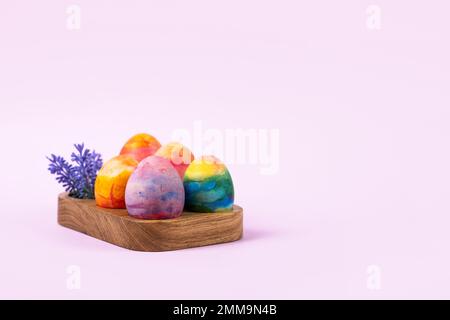 Colorful Easter eggs in a wooden egg stand on a lilac background. Happy Easter concept. Greeting card. Stock Photo