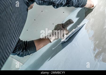 man applies insulation to a bathroom wall Stock Photo