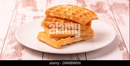 Delicious Belgian waffles served on white plate and wooden background, rustic concept, space for text Stock Photo