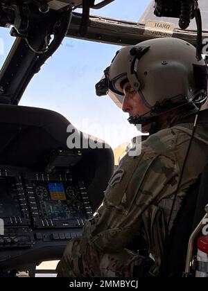 U.S. Army Chief Warrant Officer 2 Christopher Hansen, a Clifton Park, NY, native, UH-60M Black Hawk Pilot and Aviation Mission Survivability Officer for Alpha Company, 3-142nd Assault Helicopter Battalion (AHB), based out of Latham, New York, inspects data from a center console monitor during start-up procedures of a UH-60M Black Hawk at Camp Buehring, Kuwait, Sept. 16, 2022. Hansen and his crew surveyed landing zones in the vicinity of Camp Buehring during their flight. 3-142nd AHB, attached to 36th Combat Aviation Brigade, currently supports the Combined Joint Task Force - Operation Inherent Stock Photo