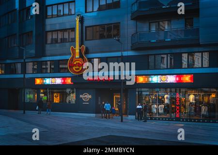 Andorra la Vella, Jan 2020 People at Hard Rock Caffe with big neon guitar and shop display in capital city of Andorra, Pyrenees Mountains Stock Photo
