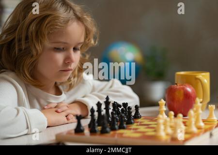 Clever concentrated and thinking kid boy playing chess. Brain development and logic. Stock Photo