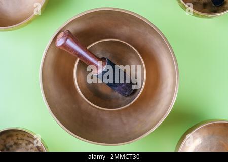 Tibetan singing bowls with sticks, used during mantra meditations on green background, flat lay, web banner Stock Photo