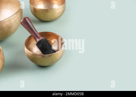 Tibetan singing bowls with sticks used during mantra meditations on green background, close up, copy space Stock Photo