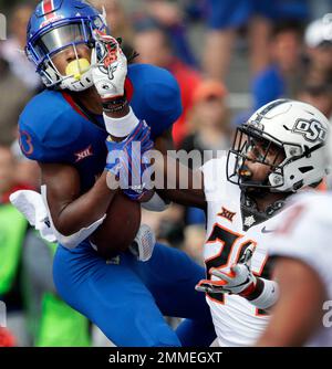 Kansas wide receiver Kwamie Lassiter II (83) catches a touchdown pass while  covered by Oklahoma State safety Jarrick Bernard (24) during the first half  of an NCAA college football game in Lawrence