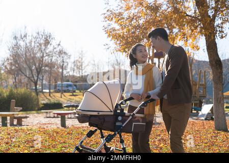 A young couple walk pushing a stroller Stock Photo