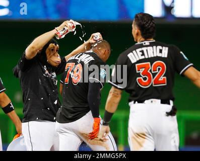 Wearing a monkey mask, Miami Marlins' Miguel Rojas, top, prepares to hit  J.T. Realmuto with a shaving cream pie as Realmuto does a postgame  interview after a baseball game against the Atlanta