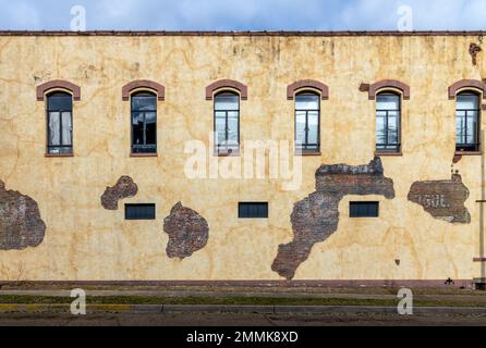 Old brick wall with  windows and damaged pieces of plaster in Marshall, Texas Stock Photo