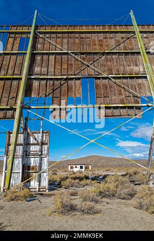 The concession stand and projector building is framed by the damaged wood screen at an abandoned drive-in movie theatre Stock Photo