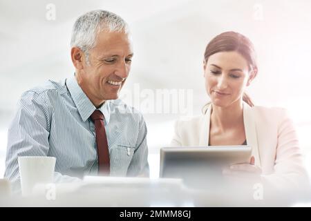 Our ideas turn into success. two coworkers sitting at a table using a digital tablet. Stock Photo