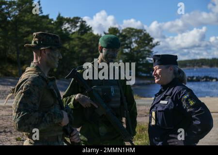 U.S. Marine Corps Capt. Brandon Klewicki (left), and Swedish Marine Capt. Jacob Lindholm (center), joint commanders of the ground force element, greet Swedish Navy Rear Admiral Ewa Skoog Haslum (right), Chief of Swedish Navy, while visiting U.S. and Swedish Marines during exercise Archipelago Endeavor 22 (AE22) on Berga Naval Base, Sweden, Sept. 21, 2022. AE22 is an integrated field training exercise that increases operational capability and enhances strategic cooperation between the U.S. Marines and Swedish forces. Stock Photo