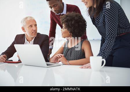 Success, lets reach it together. a group of businesspeople discussing something on a laptop. Stock Photo