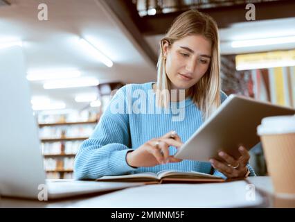 Education, university and woman in library with tablet, research and books for school project or exam. Laptop, notebook and internet, college student Stock Photo