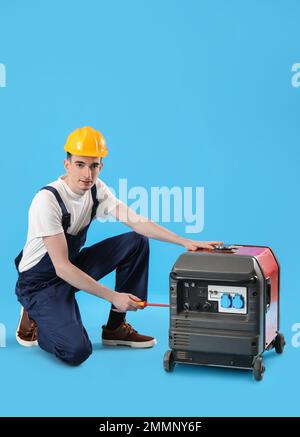 Male worker repairing portable gasoline generator on blue background Stock Photo