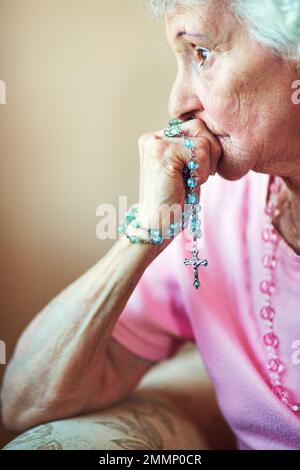 Calling on the comfort of Christ. Cropped shot an elderly woman holding a rosary in prayer. Stock Photo