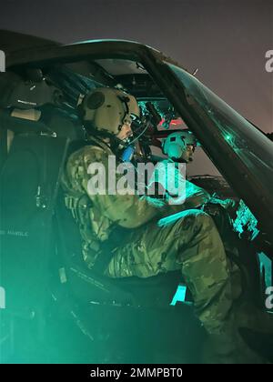 U.S. Army Chief Warrant Officer 2 Christopher Gallant, UH-60M Black Hawk Pilot and Mission Planner for Bravo Company, 3rd Battalion, 142nd Aviation Regiment, Assault Helicopter Battalion, attached to 36th Combat Aviation Brigade (right), along with Chief Warrant Officer 2 Christopher Hansen, UH-60M Black Hawk Pilot and Aviation Mission Survivability Officer for Alpha Company, 3-142nd AHB (left), conducts start-up procedures of a UH-60M Black Hawk at Camp Buehring, Kuwait, Sept. 21, 2022. Gallant and his crew surveyed landing zones at night in the vicinity of Camp Buehring during their flight. Stock Photo