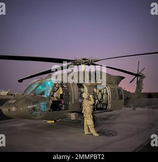 Chief Warrant Officer 2 Christopher Hansen, a Clifton Park, UH-60M Black Hawk Pilot and Aviation Mission Survivability Officer for Alpha Company, 3rd Battalion, 142nd Aviation Regiment, Assault Helicopter Battalion, attached to 36th Combat Aviation Brigade, and 1st Sgt. Amy Klemm, UH-60M Crew Chief and Flight Instructor for Bravo Company, 3-142nd AHB, adjust their night vision goggles to  their optimal sight points at Camp Buehring, Kuwait, Sept. 21, 2022. Hansen and his crew surveyed landing zones in the vicinity of Camp Buehring during a night flight. The night vision equipment aids the crew Stock Photo