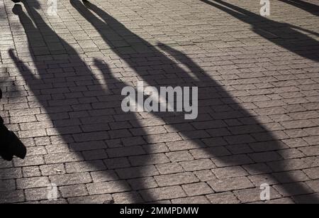 Shadows on pavement of two People walking under bright sunlight. Stock Photo