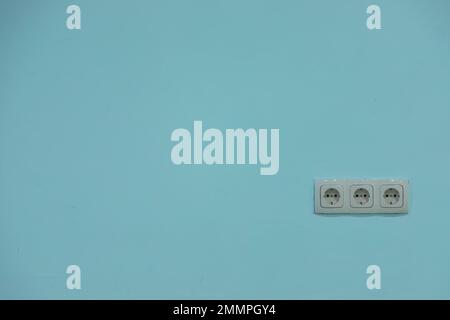 white electrical outlet on a blue wall, background. Stock Photo