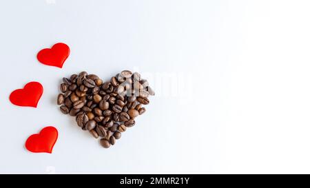 Symbol of love for coffee. Heart shape made from coffee beans and red hearts on white background, close up, top view, flat lay, copy space, banner Stock Photo
