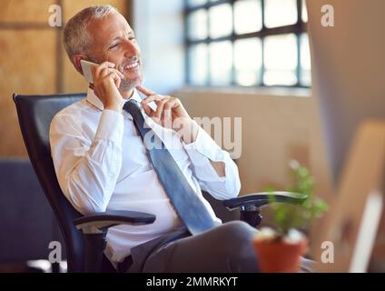 Interestingtell me more. a mature businessman using his phone in the office. Stock Photo