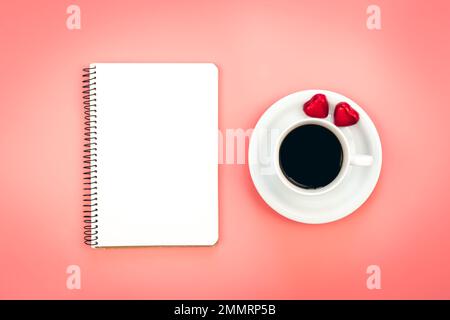 A cup of coffee, a blank notepad and heart shaped candies, top view. Stock Photo