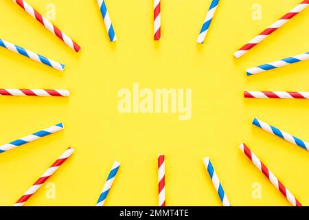 Multicolored party drinking straws arranged into a circle on yellow background. Stock Photo