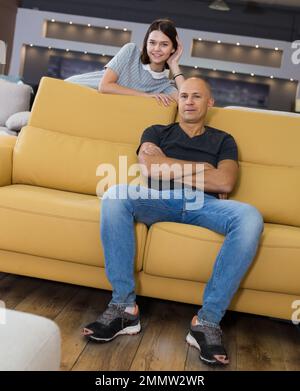 Couple sitting on yellow sofa Stock Photo