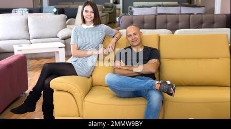 Couple sitting on yellow sofa Stock Photo