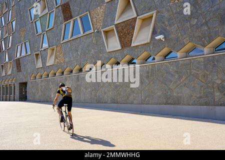 A cyclist rides on the sidewalk in front of the facade of the Grand Théâtre de la Ville de Luxembourg. Stock Photo