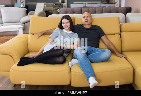Couple sitting on yellow sofa Stock Photo