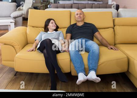 Couple sitting on yellow sofa Stock Photo