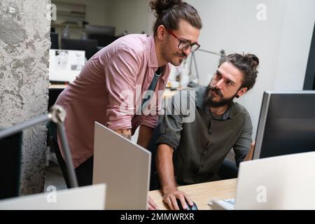 Diverse group of professionals meeting in office. IT programmers use computer, talk strategy Stock Photo