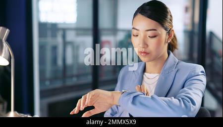 Watch, deadline and computer with a business asian woman working late at night in her office for overtime. Finance, accounting and dedication with a Stock Photo