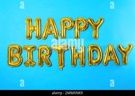 Phrase HAPPY BIRTHDAY made of foil balloon letters on light blue background Stock Photo