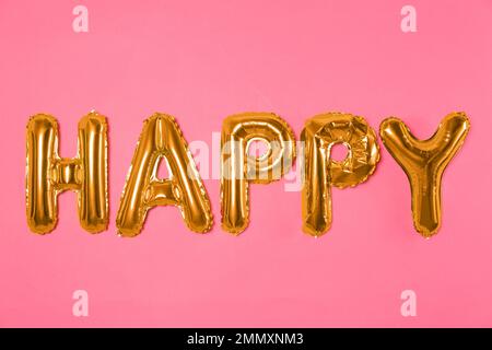 Word HAPPY made of golden foil balloons letters on pink background Stock Photo