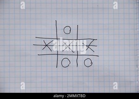 the game of tic-tac-toe is drawn with a pen on a crumpled notebook in a cage, play and rest, children's game of tic-tac-toe Stock Photo