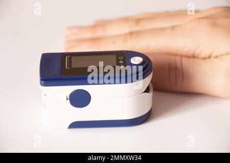 pulse oximeter on the finger of a woman on an isolated background, measure the level of oxygen in the blood, oxometer Stock Photo