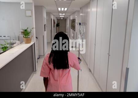 African american female patient walking through corridor with drip at hospital Stock Photo