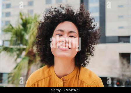 Front view of happy young hispanic woman smiling with curly hair Close up portrait of cracy lady laughing and having fun. High quality photo Stock Photo