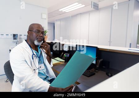 African american male doctor working at hospital, talking on telephone Stock Photo