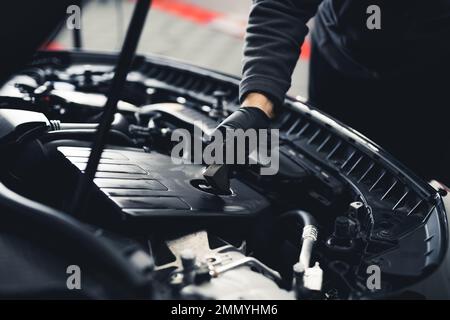 Unrecognizable man cleaning engine of a sports car. Car washing and car detailing concept.Top view. Indoor shot. High quality photo Stock Photo
