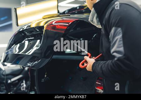 Removal of dents without painting. PDR technology for car body repair. Professional caucasian male worker during work. High quality photo Stock Photo