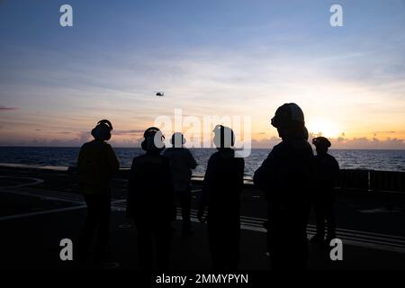 PHILIPPINE SEA (Sept. 23, 2022) – Sailors aboard the guided-missile destroyer USS Zumwalt (DDG 1000) watch as an MH-60R Sea Hawk helicopter assigned to Helicopter Maritime Strike Squadron (HSM) 35 departs the ship while operating in the Philippine Sea, Sept. 23. Zumwalt is conducting underway operations in support of a free and open Indo-Pacific. Stock Photo