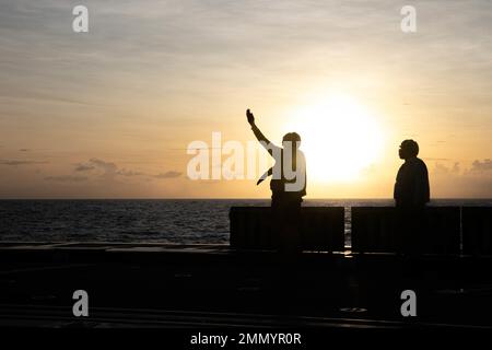 PHILIPPINE SEA (Sept. 23, 2022) – Boatswain’s Mate 2nd Class Christopher Treanor, from Mapleton, Minnesota, signals to land an MH-60R Sea Hawk helicopter assigned to Helicopter Maritime Strike Squadron (HSM) 35 aboard the guided-missile destroyer USS Zumwalt (DDG 1000) while operating in the Philippine Sea, Sept. 23. Zumwalt is conducting underway operations in support of a free and open Indo-Pacific. Stock Photo